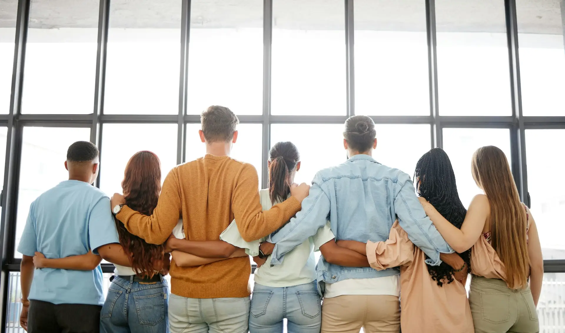 Trust, community and business team with vision looking out of a window, rear view embrace in suppor