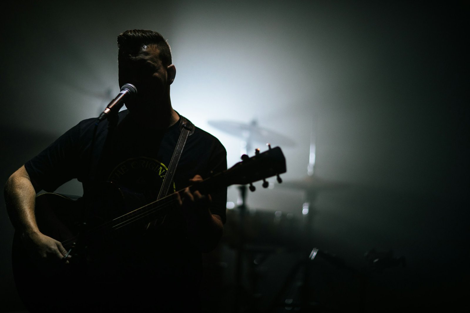 Guy singing in a worship band at church with his guitar